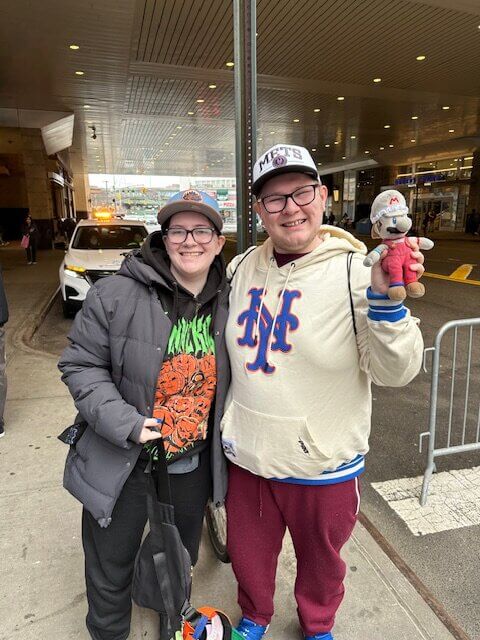 Couple wearing New York Mets gear showing their fandom and team pride at a local event.