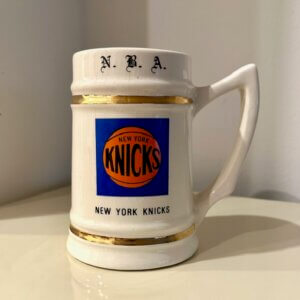6‑inch New York Knicks ceramic mug with blue‑and‑orange team logo, NBA branding on top, and “New York Knicks” lettering on the bottom.
